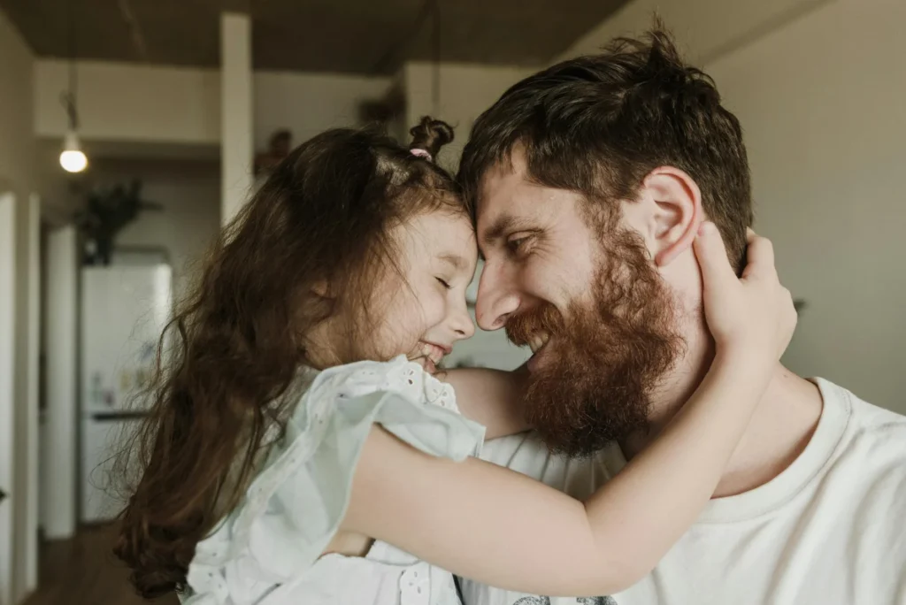 A father and daughter embrace indoors, showcasing love and happiness.
