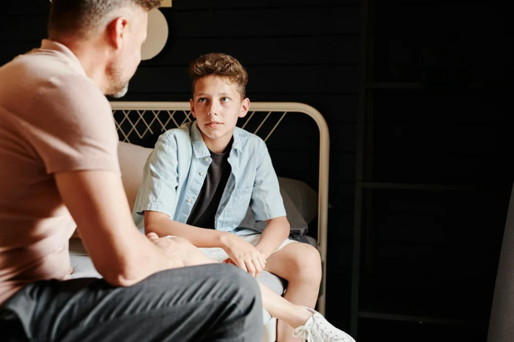 A father and son share a heartfelt conversation indoors, capturing a moment of bonding.