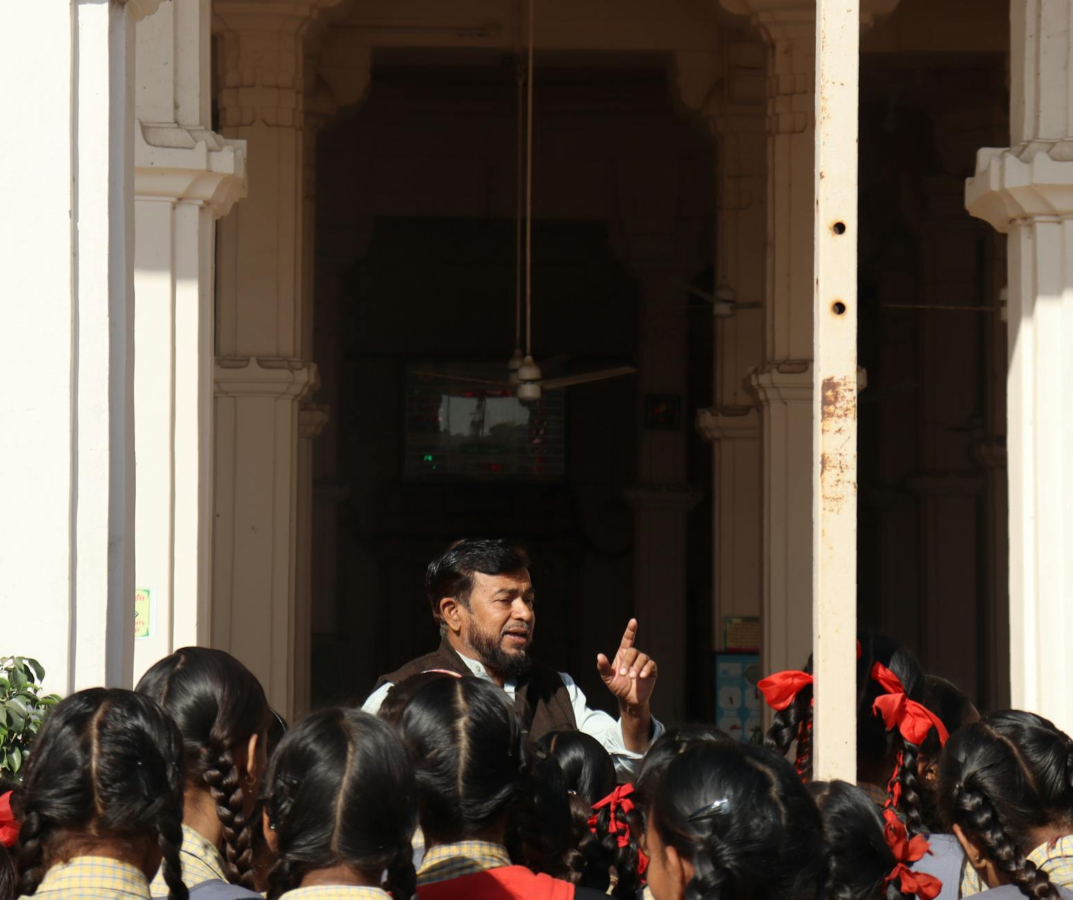 A teacher instructs schoolgirls in a historic building.