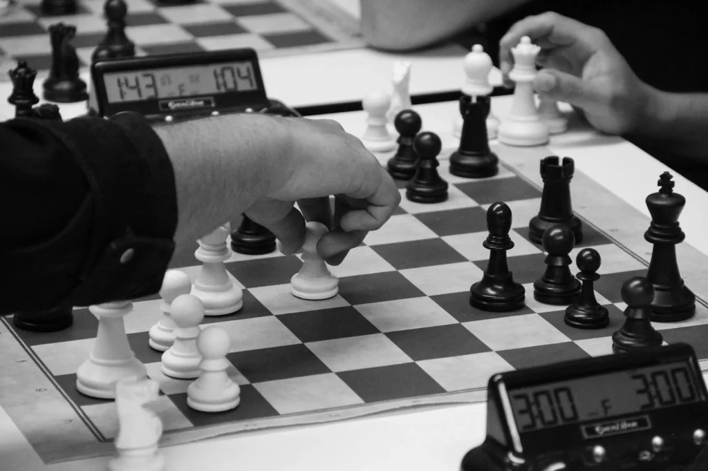 Close-up of a strategic chess match in progress, highlighting focused hands and chess pieces.