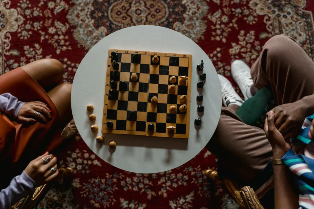 Overhead view of a chess game between two people seated indoors, focused on strategy.