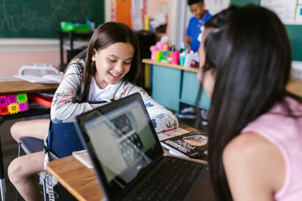 Children engaged in learning with a laptop in a vibrant classroom.