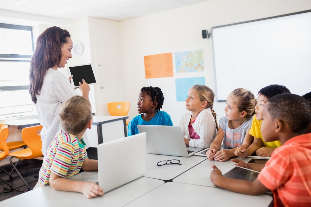 teacher holding tablet in front of students